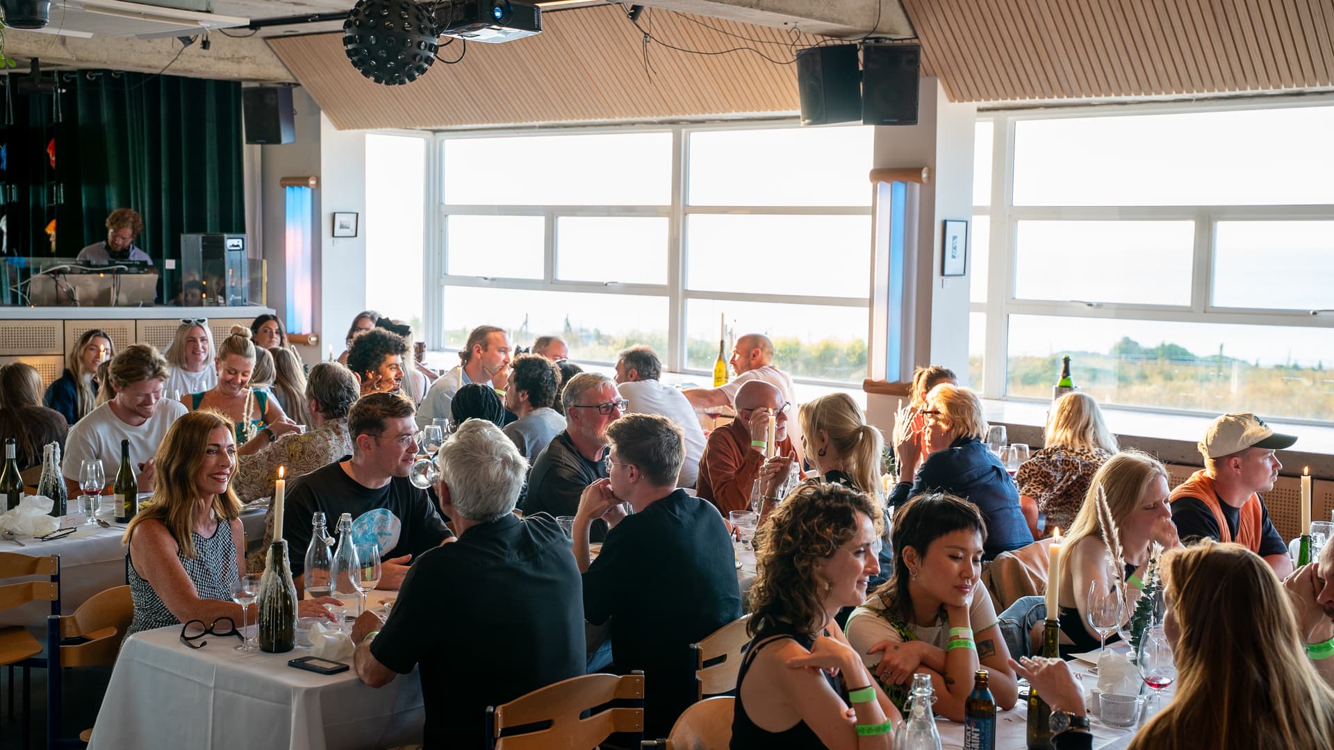 A full dining room at lunchtime, with the sea through the windows